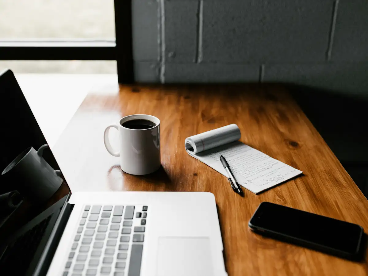 Quiet home workspace with a laptop, notebook, and headphones